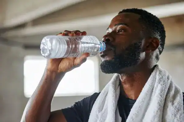 Image of man drinking water to improve hydration Hertfordshire after work out.